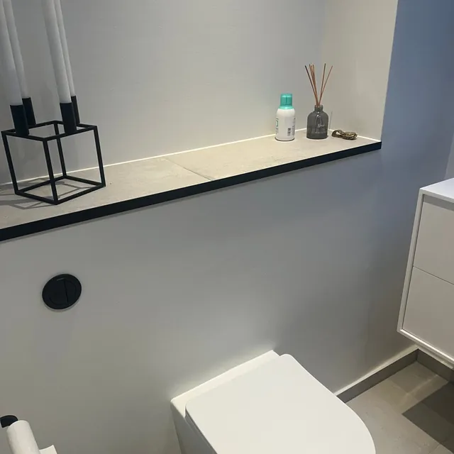 Færdigt badeværelse med væghængt toilet og hylde